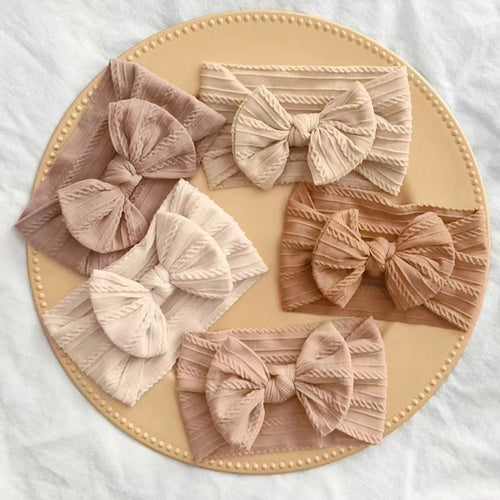 Collection of decorative bows on a round beige plate with a white background